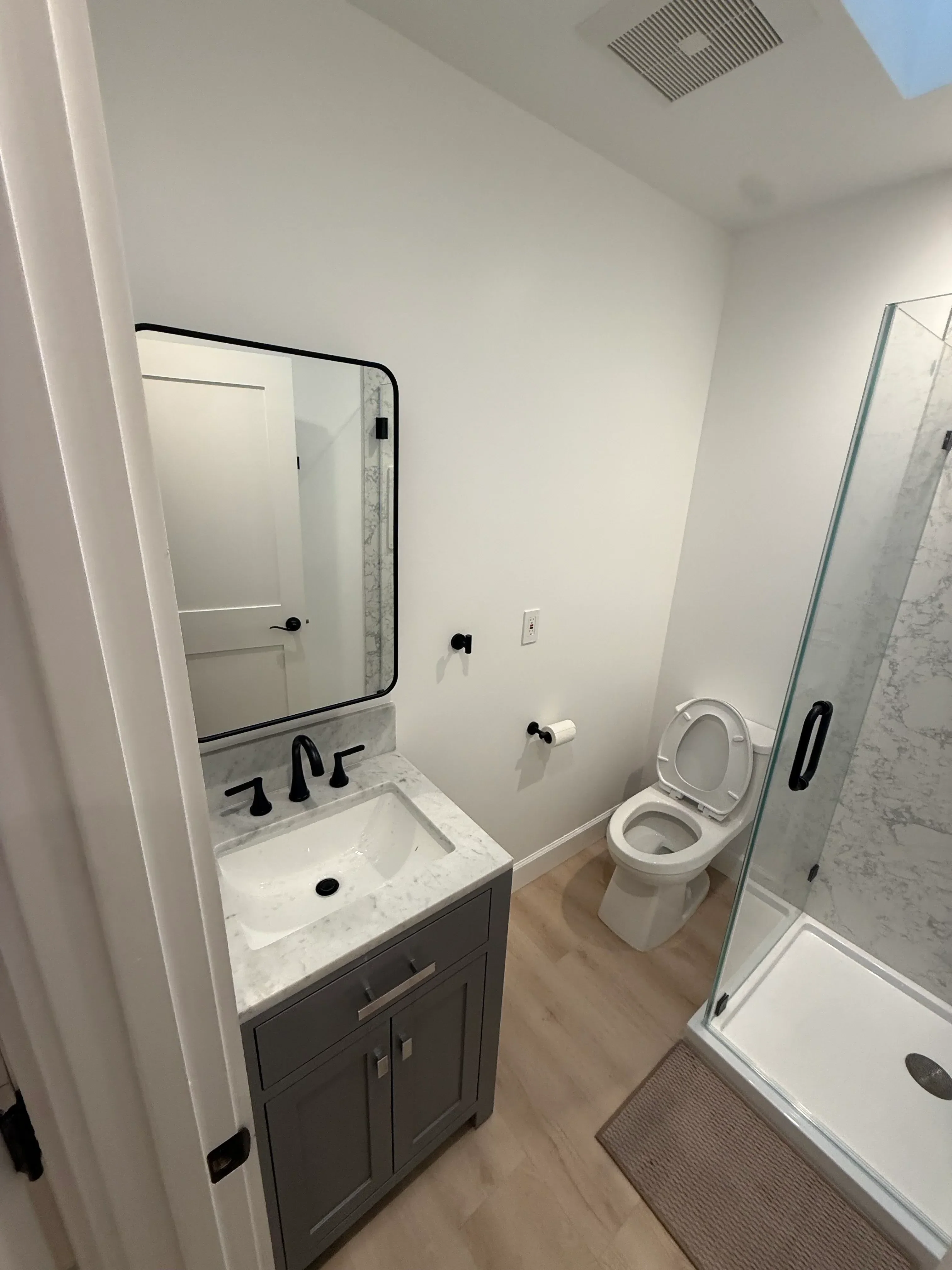 Overhead view of renovated bathroom with marble vanity, white walls, and tile flooring