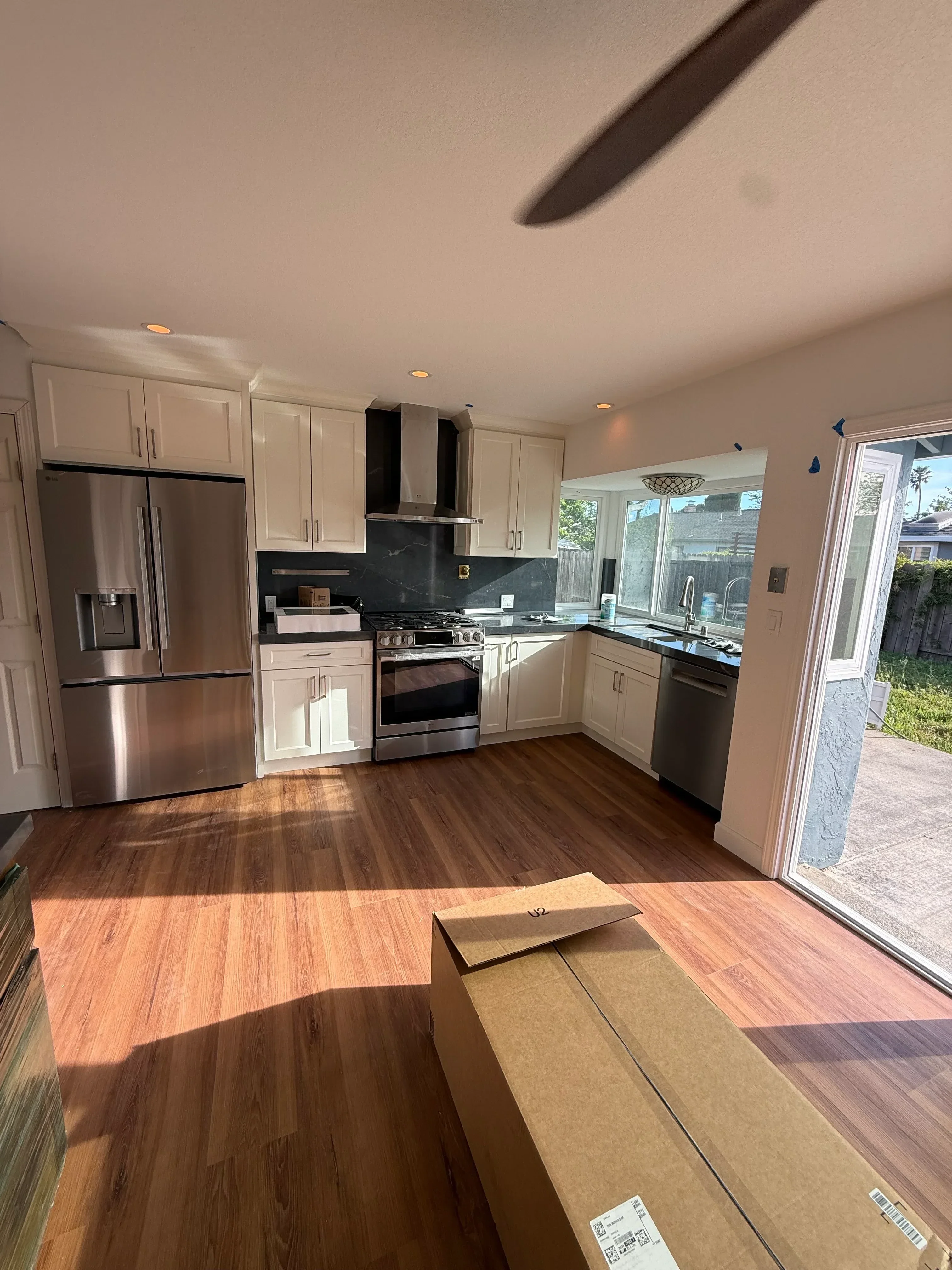 Modern kitchen with cream cabinetry, stainless steel appliances, slate backsplash, and hardwood flooring
