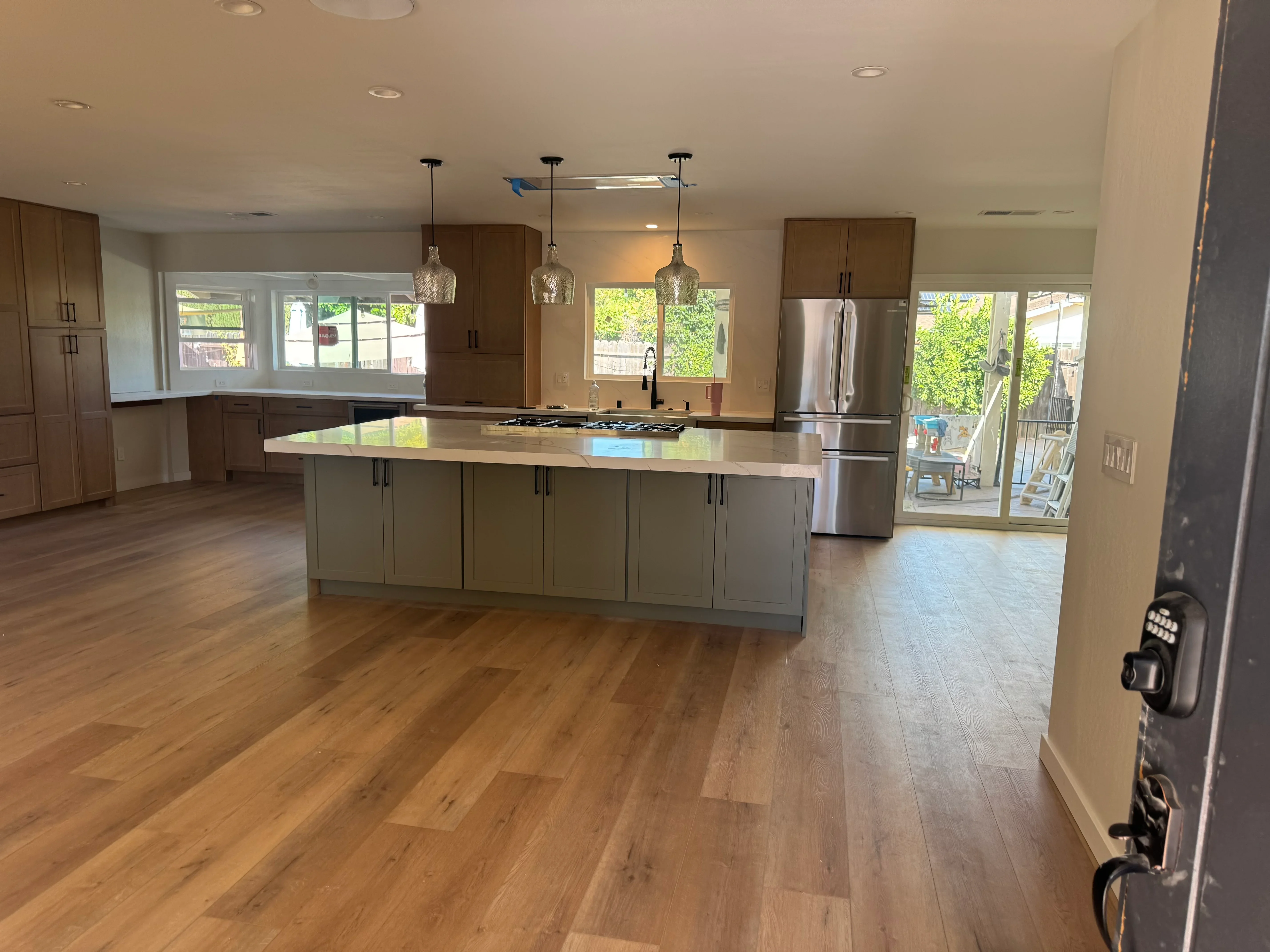 Modern kitchen with wood cabinetry, gray island, quartz counters, stainless appliances, and pendant lighting