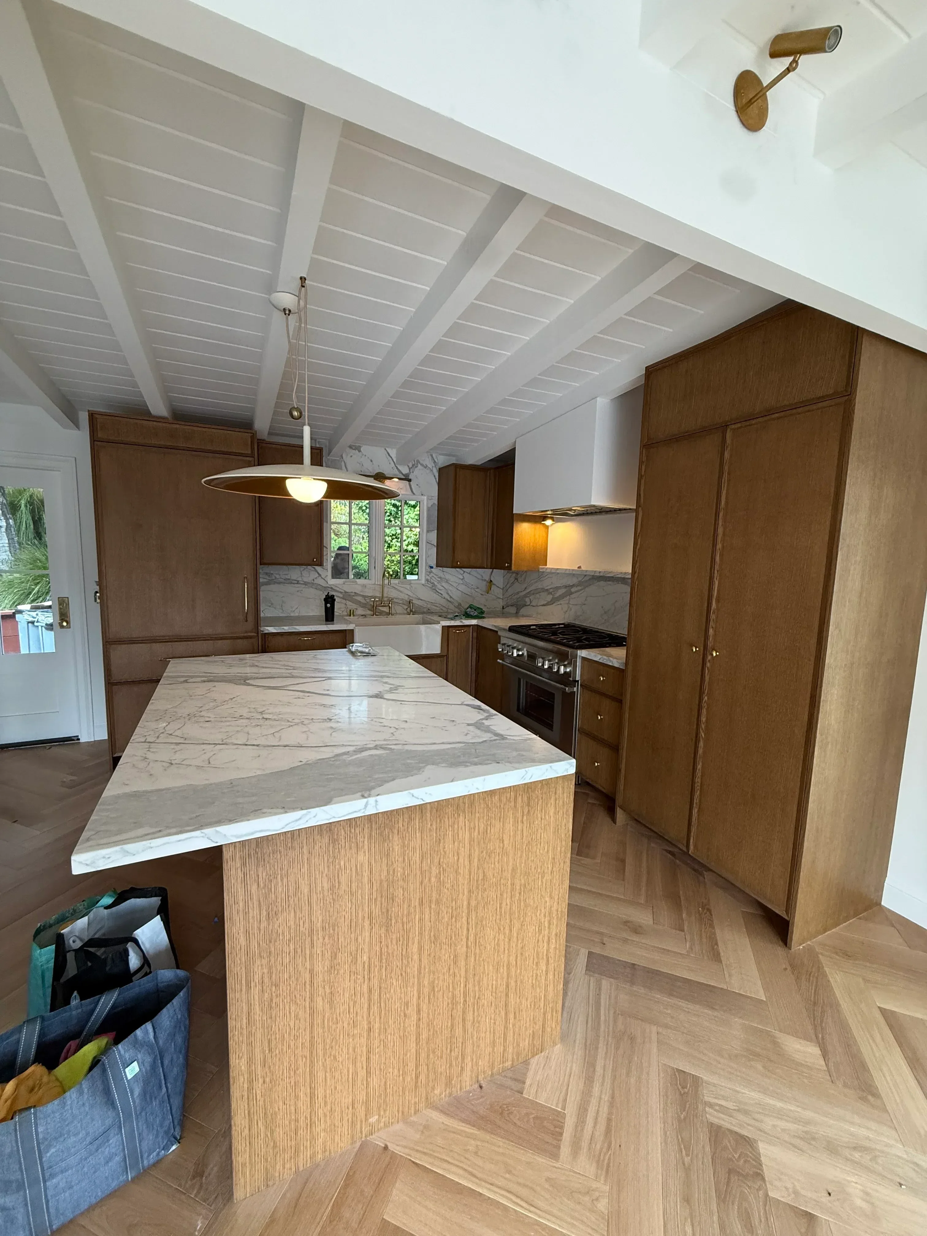 Kitchen bathroom remodel with wood cabinets, marble tile, herringbone flooring, and white shiplap walls