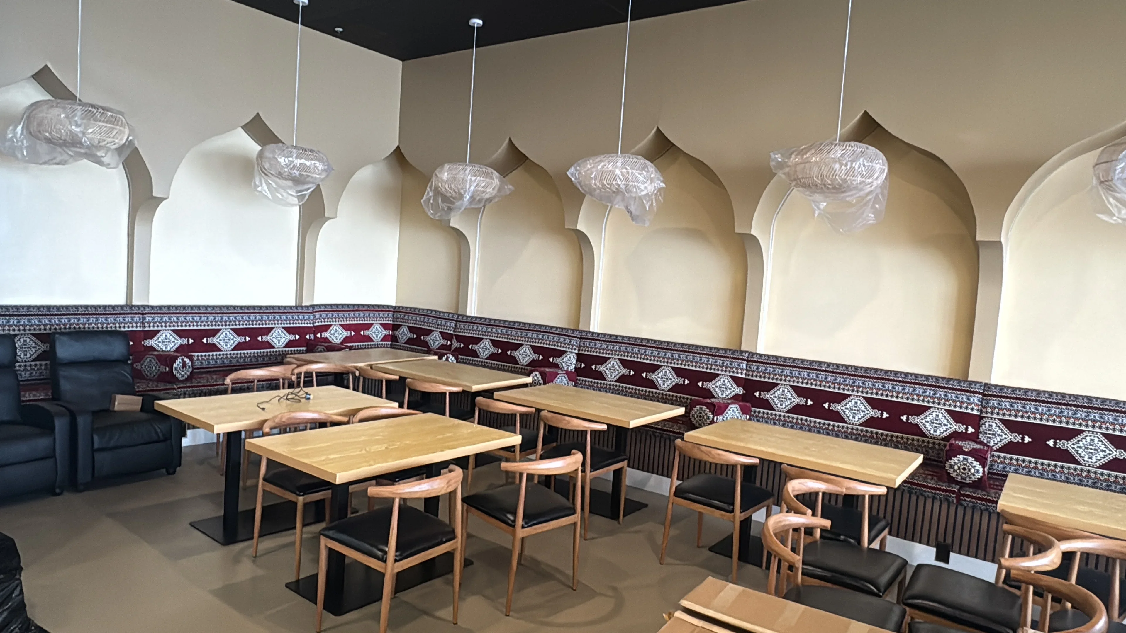 Commercial dining room with arched wall alcoves, decorative tile wainscoting, wood tables, and pendant lighting