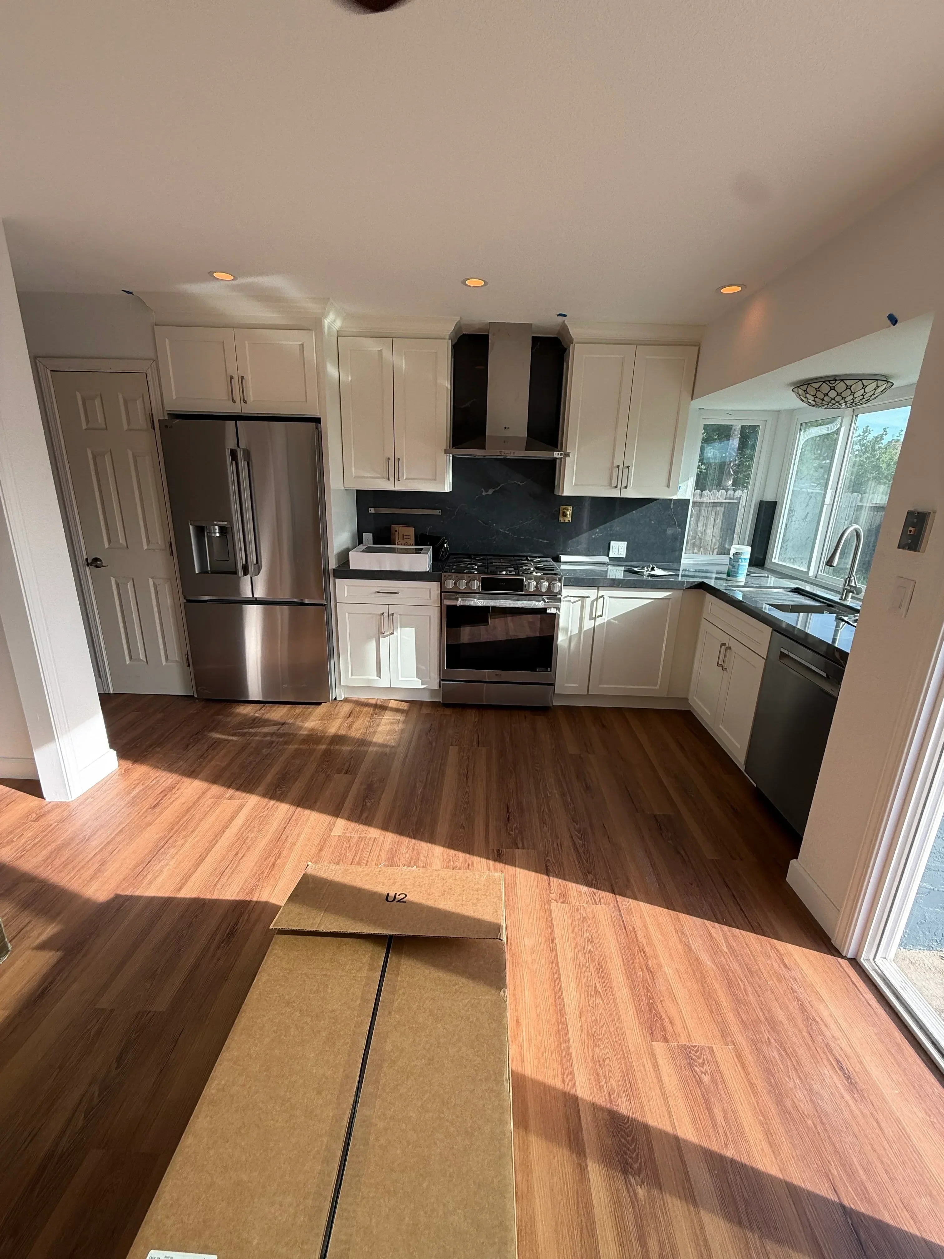 Kitchen remodel with cream cabinetry, stainless steel appliances, wood flooring, and skylight