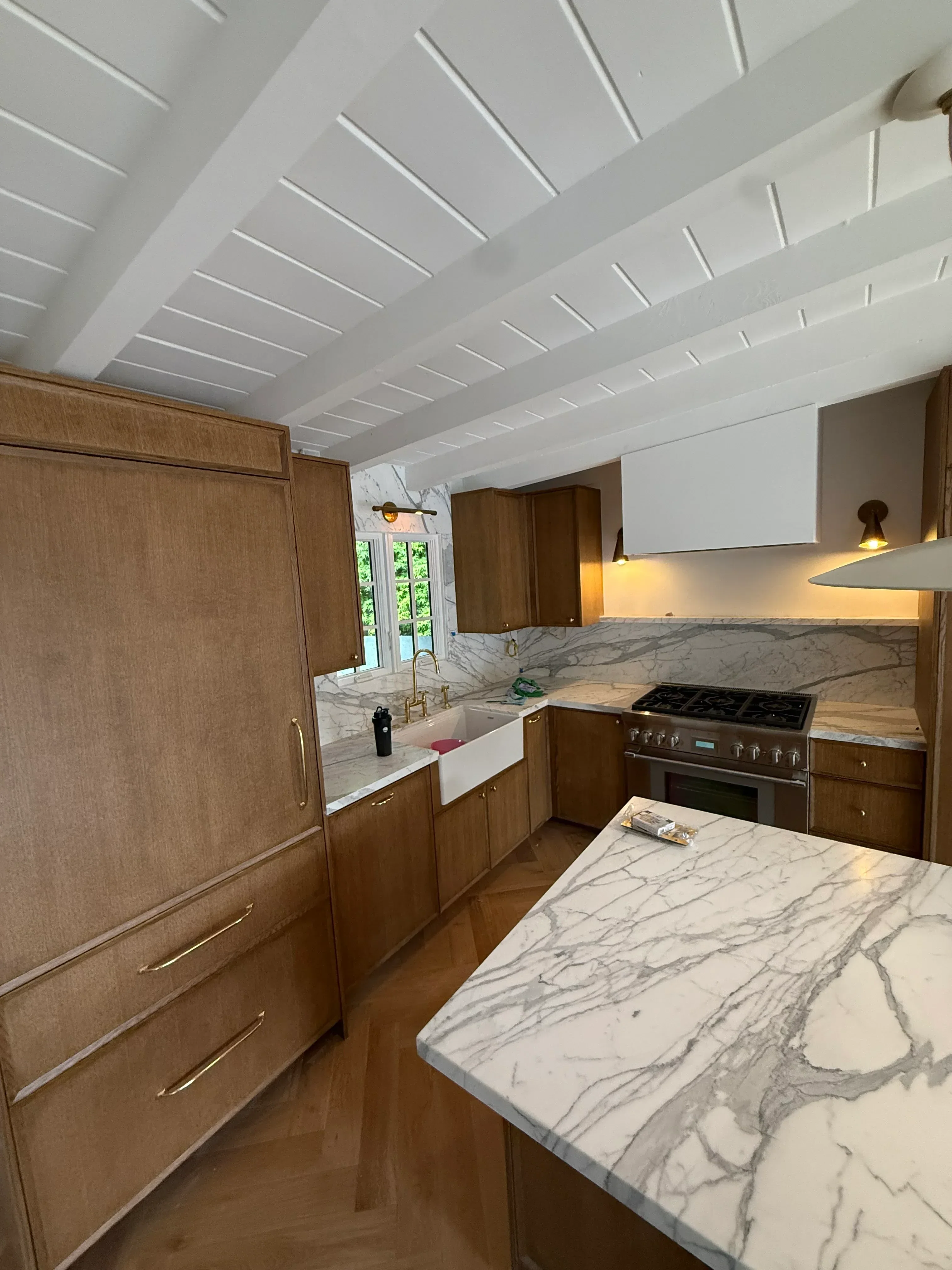 Kitchen with marble countertops, white cabinetry, and wood flooring during remodeling