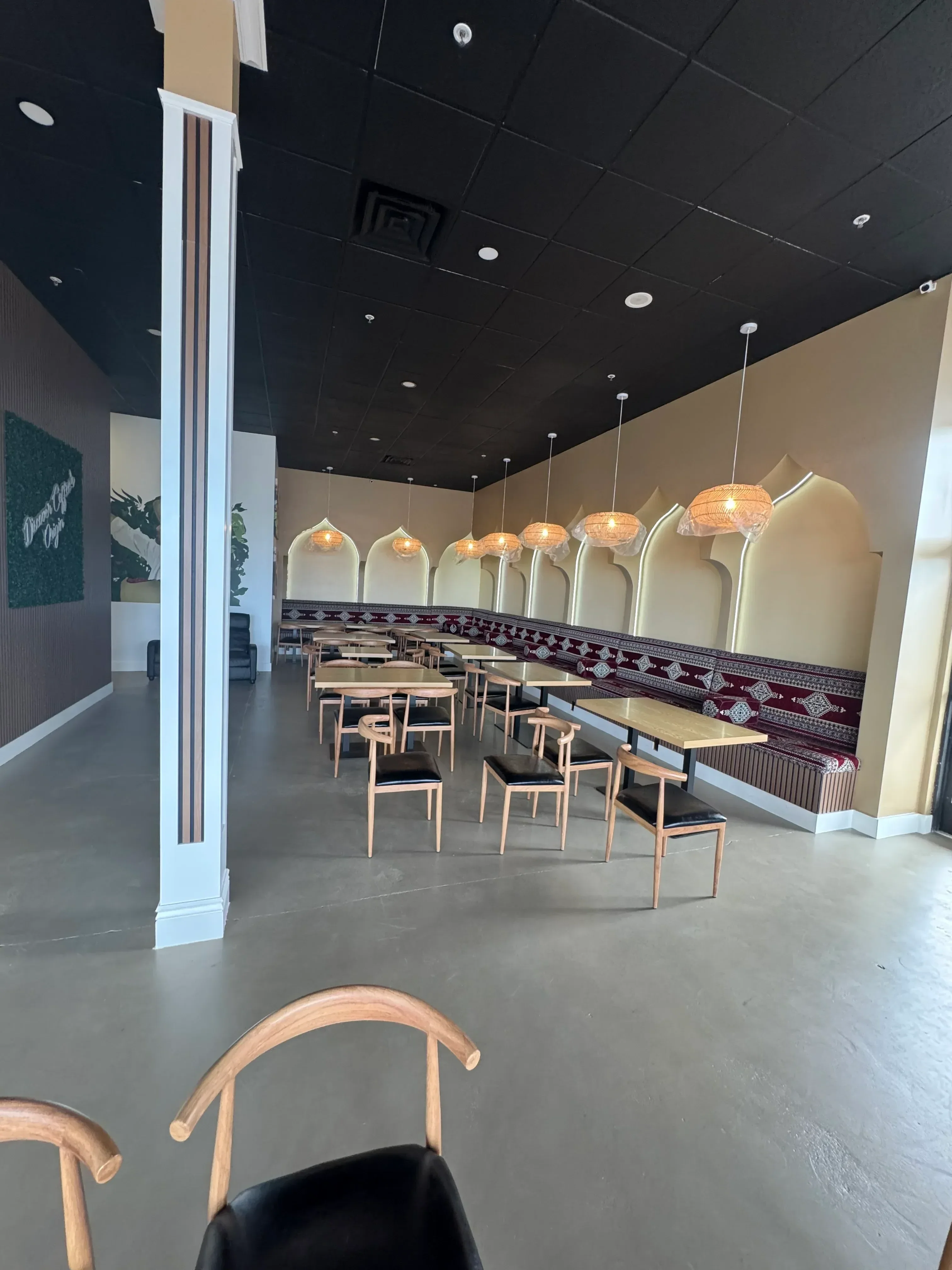 Black tile wall, cream ceiling with recessed lights, pendant fixtures, wood framing, polished concrete flooring